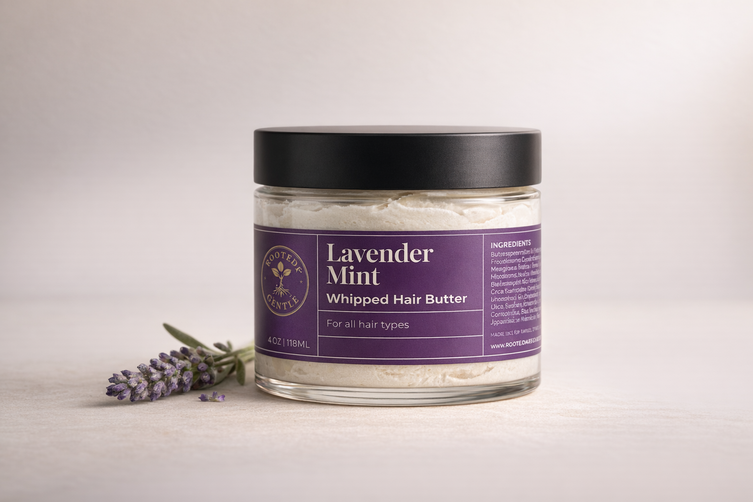 Lavender Mint Whipped hair butter by Rooted & Gentle in a clear glass bottle with a purple label on a beige background.